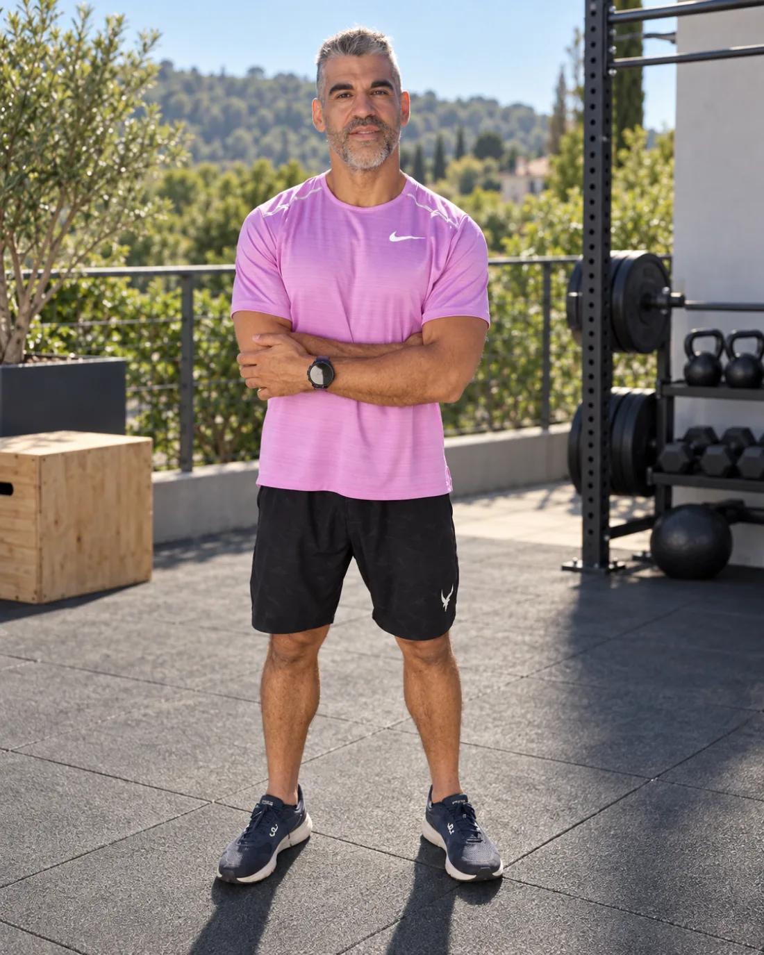 Anibal Bonan, bras croisés sur la terrasse d'entraînement d'A Ton Sport, devant le rack et les kettlebells.