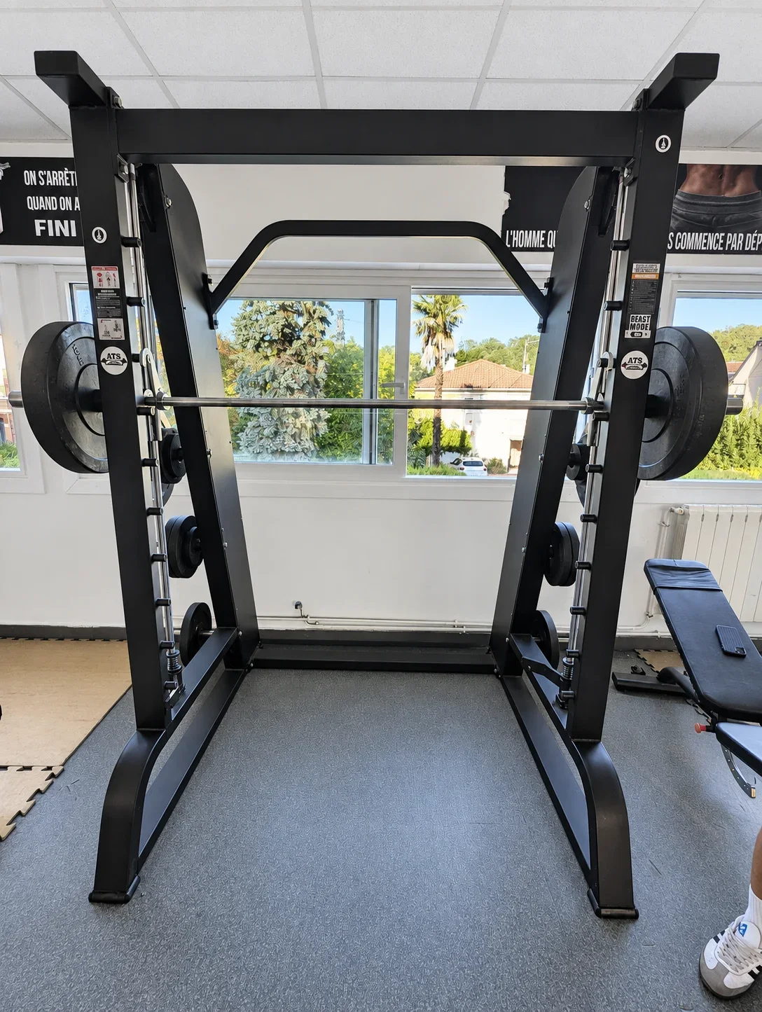 Smith machine avec barre guidée et disques.