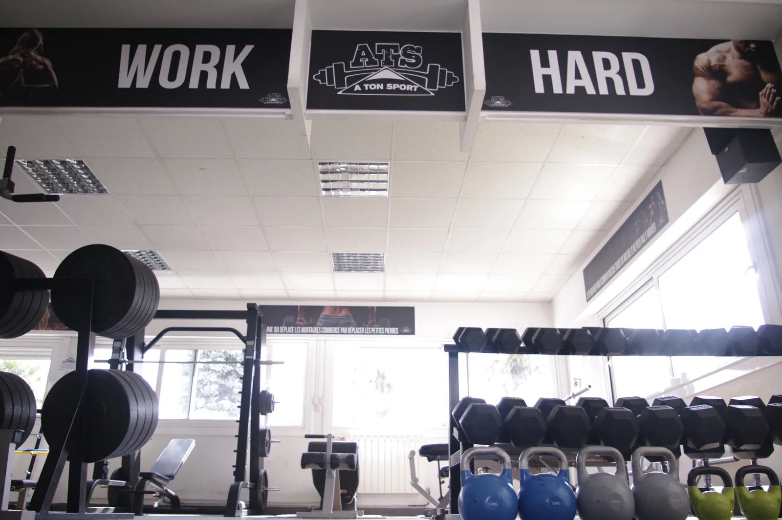Vue intérieure de la salle A Ton Sport avec racks, haltères et kettlebells.
